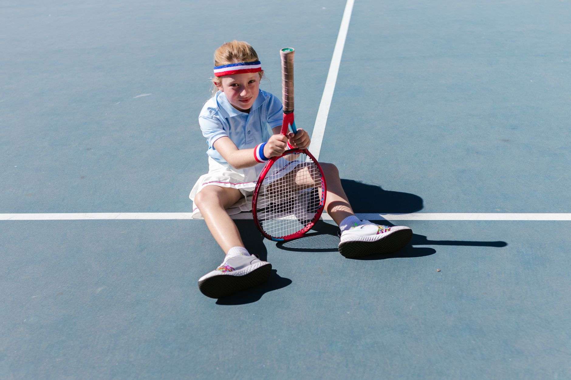 A tennis racket and ball on a hard tennis court