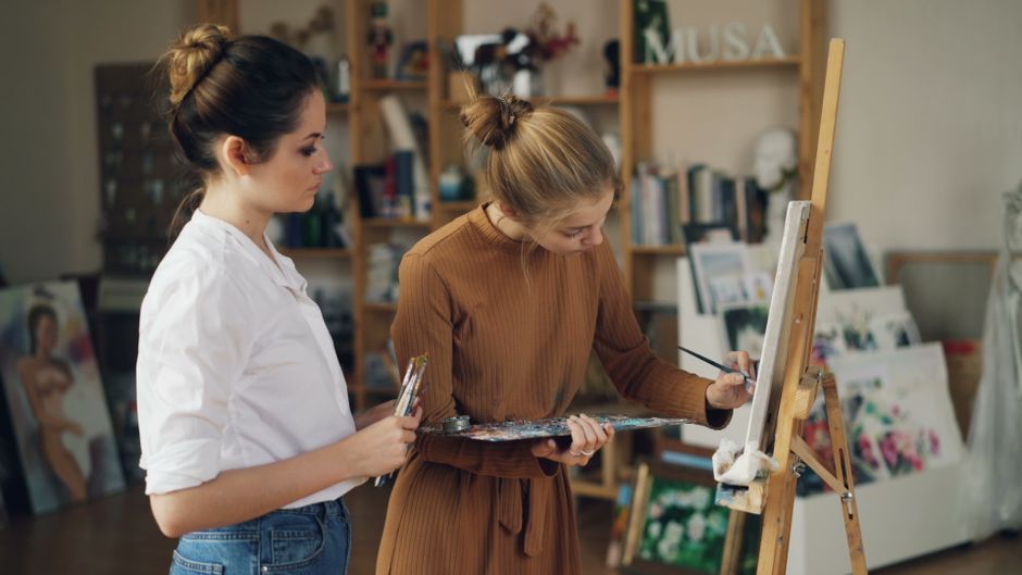 An easel holding a canvas with a coastal scene in progress during an art class