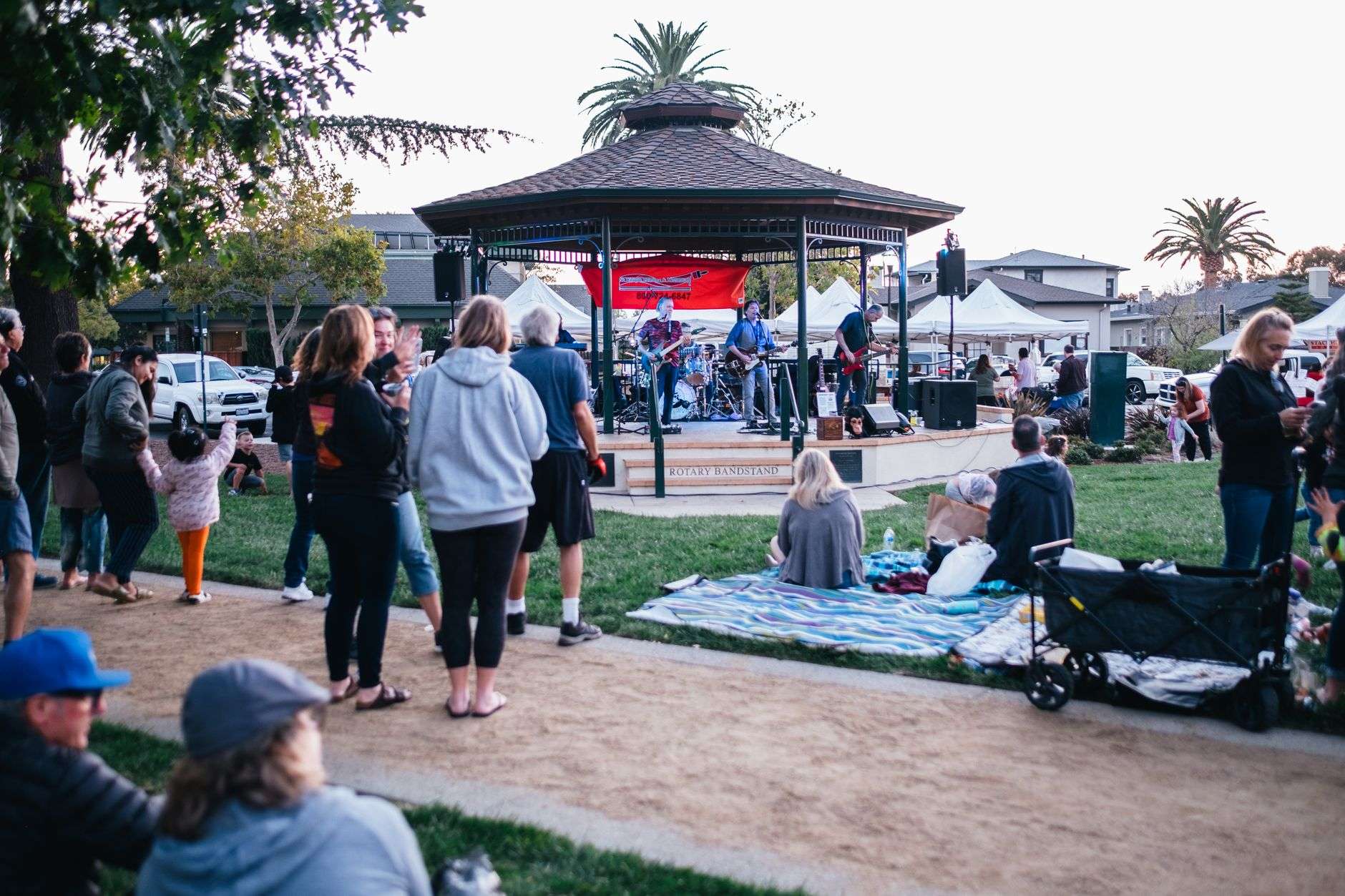 Brass and woodwind musicians performing at an outdoor evening concert