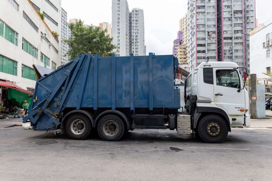 A garbage truck travels down a quiet residential street