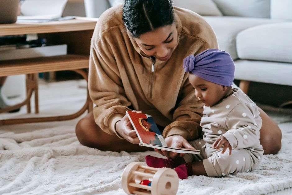 A parent holding a board book open for a baby