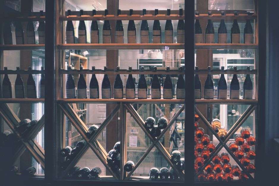 Rows of wine bottles displayed on wooden shelves in a wine shop