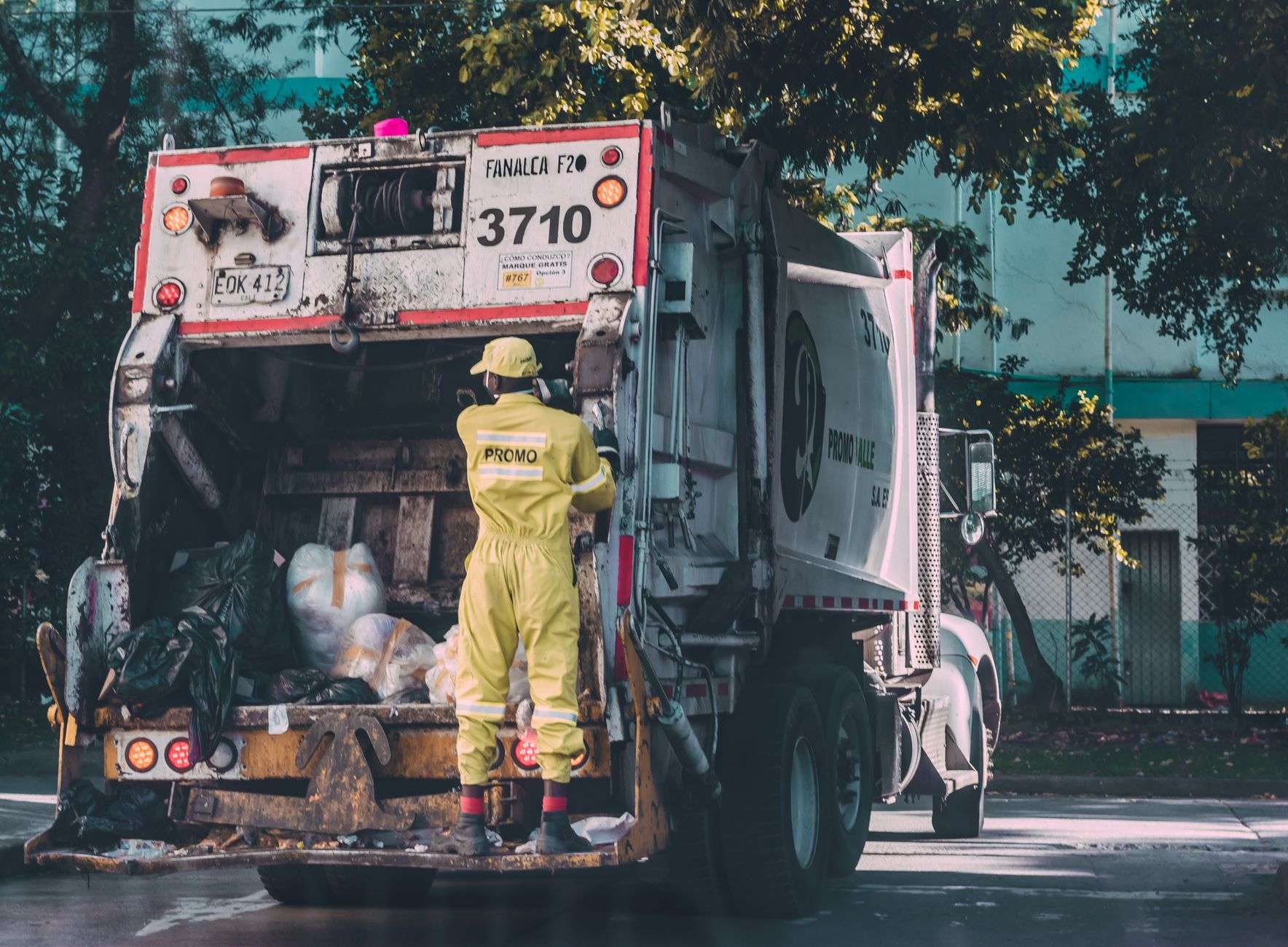 A garbage collection truck servicing carts on a residential street, illustrating a county waste hauling contract