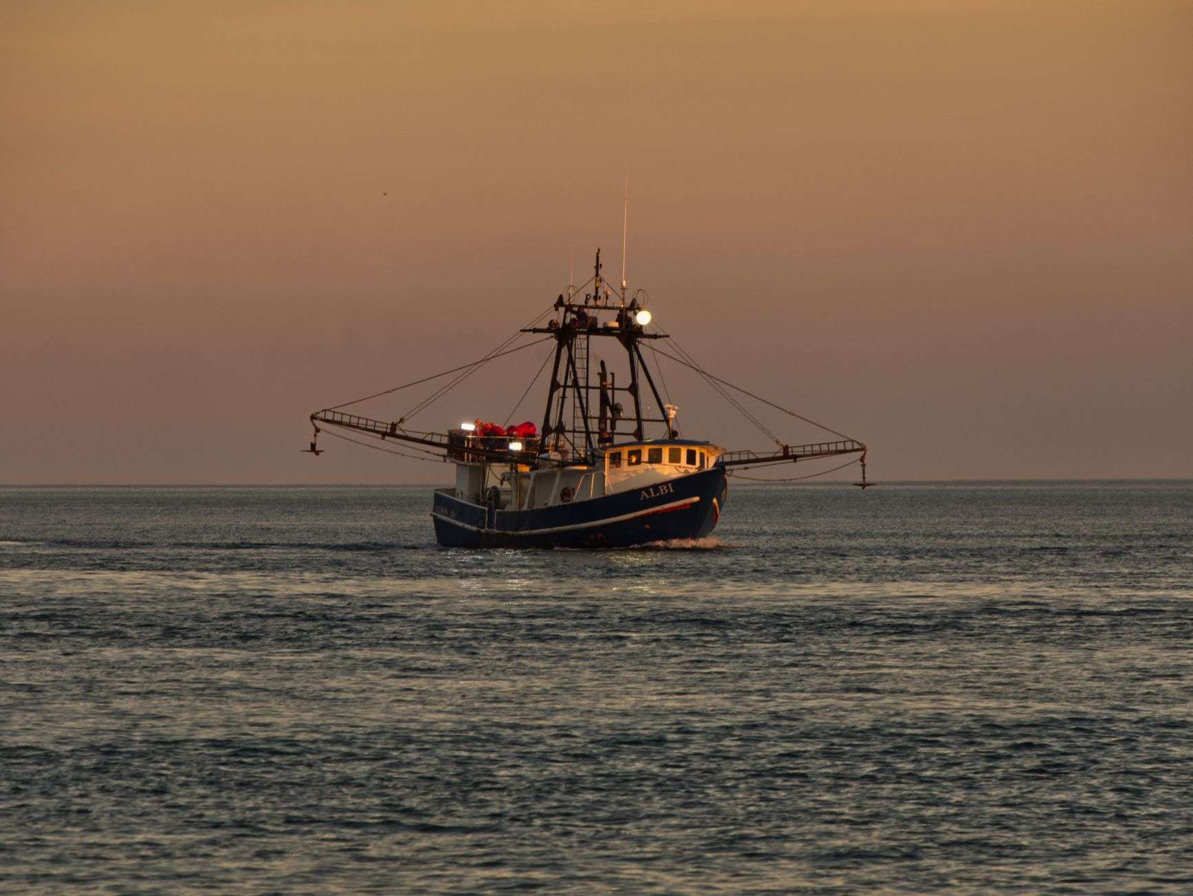 A fishing trawler on the ocean at sunset