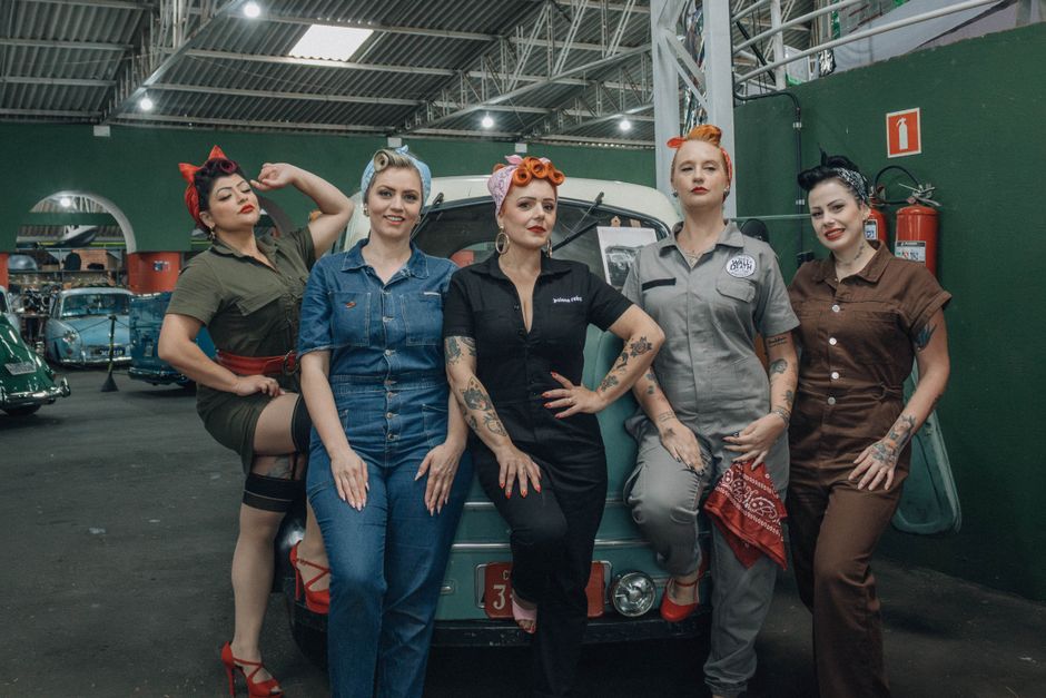 A polished classic car from the fifties parked at an outdoor music festival