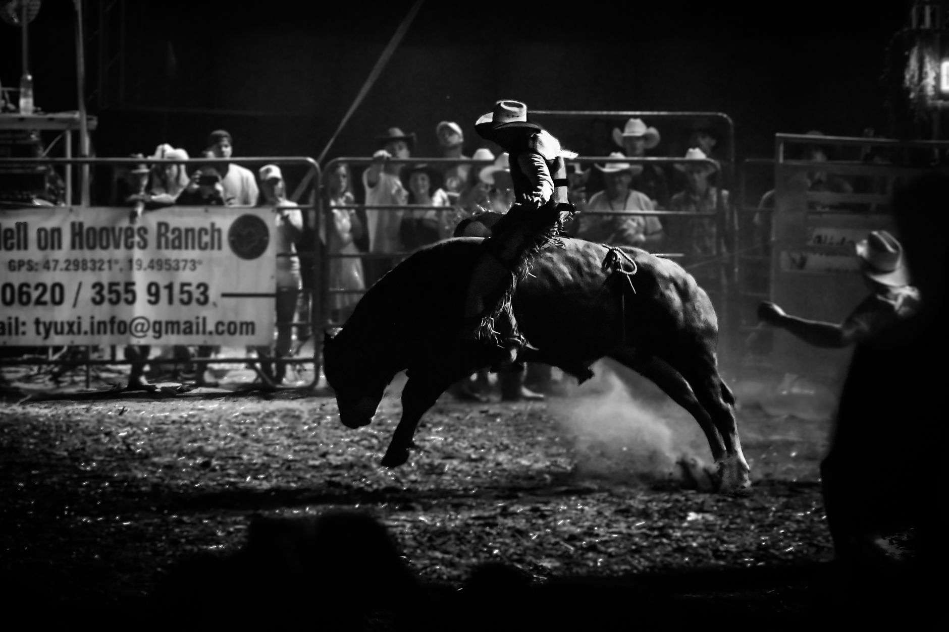 A rodeo competitor rides in a dirt arena under stadium lights