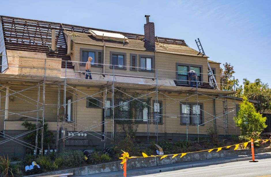 Roofing contractors working on the roof of a residential home