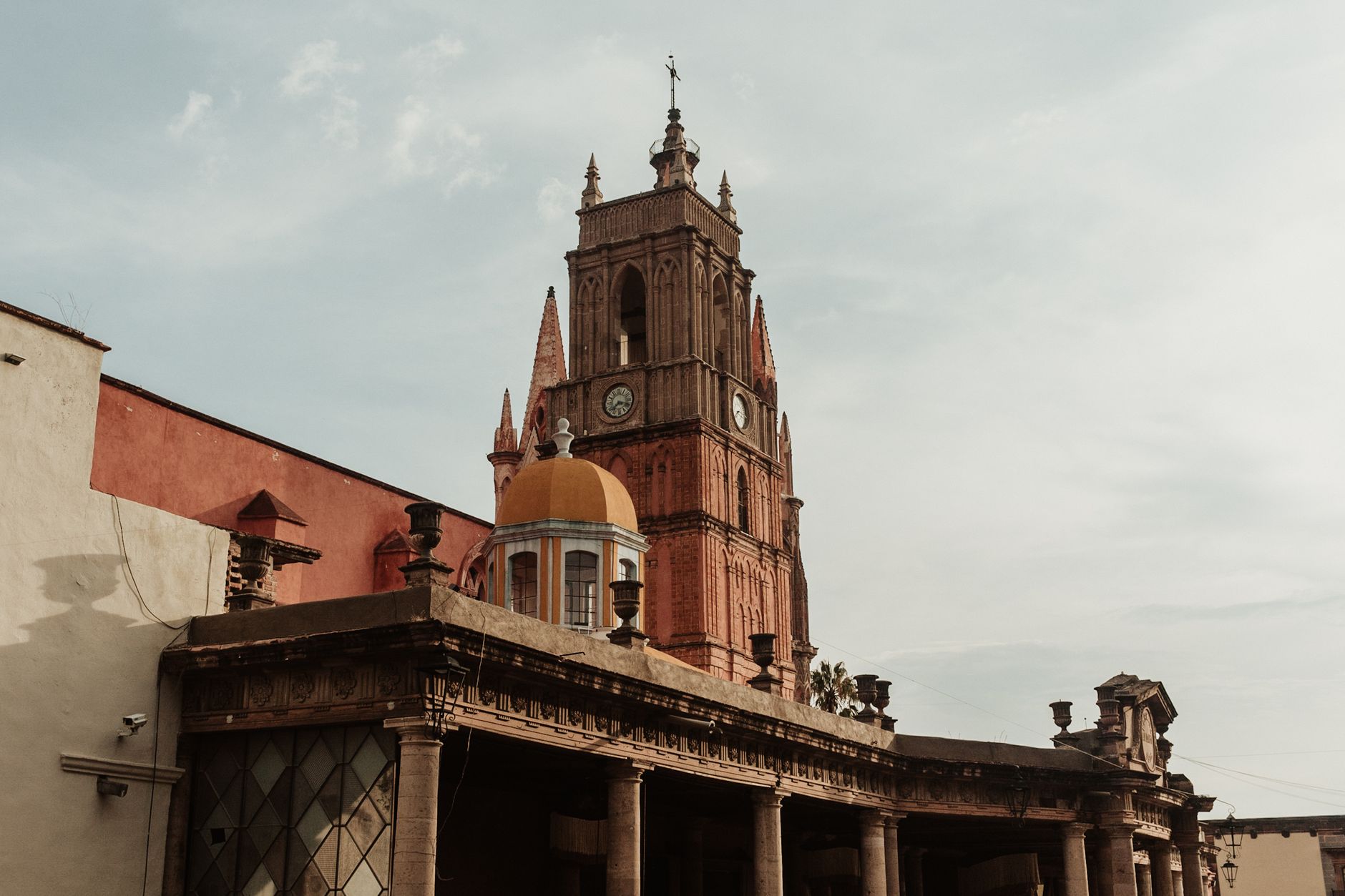 Colorful colonial buildings and a pink stone church tower in a Mexican highland city