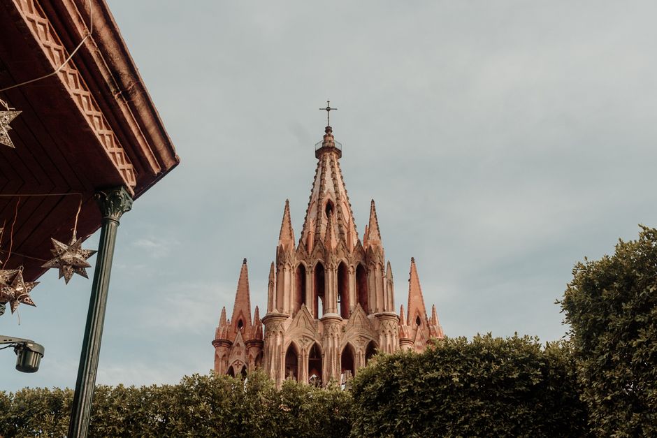 The neo-gothic pink towers of the Parroquia de San Miguel Arcangel above a plaza in Mexico