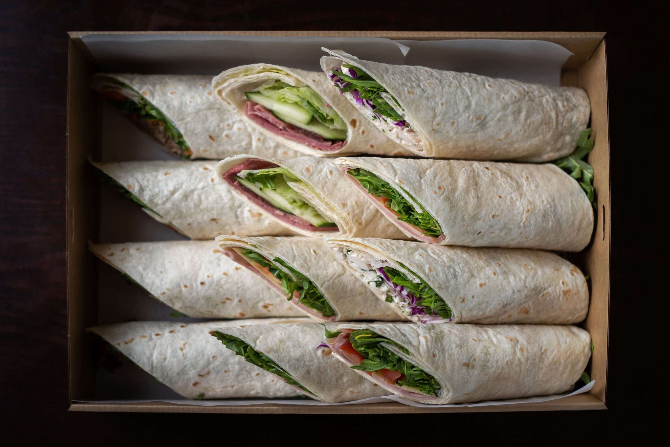 Sandwich wraps sliced and packed in a takeout box