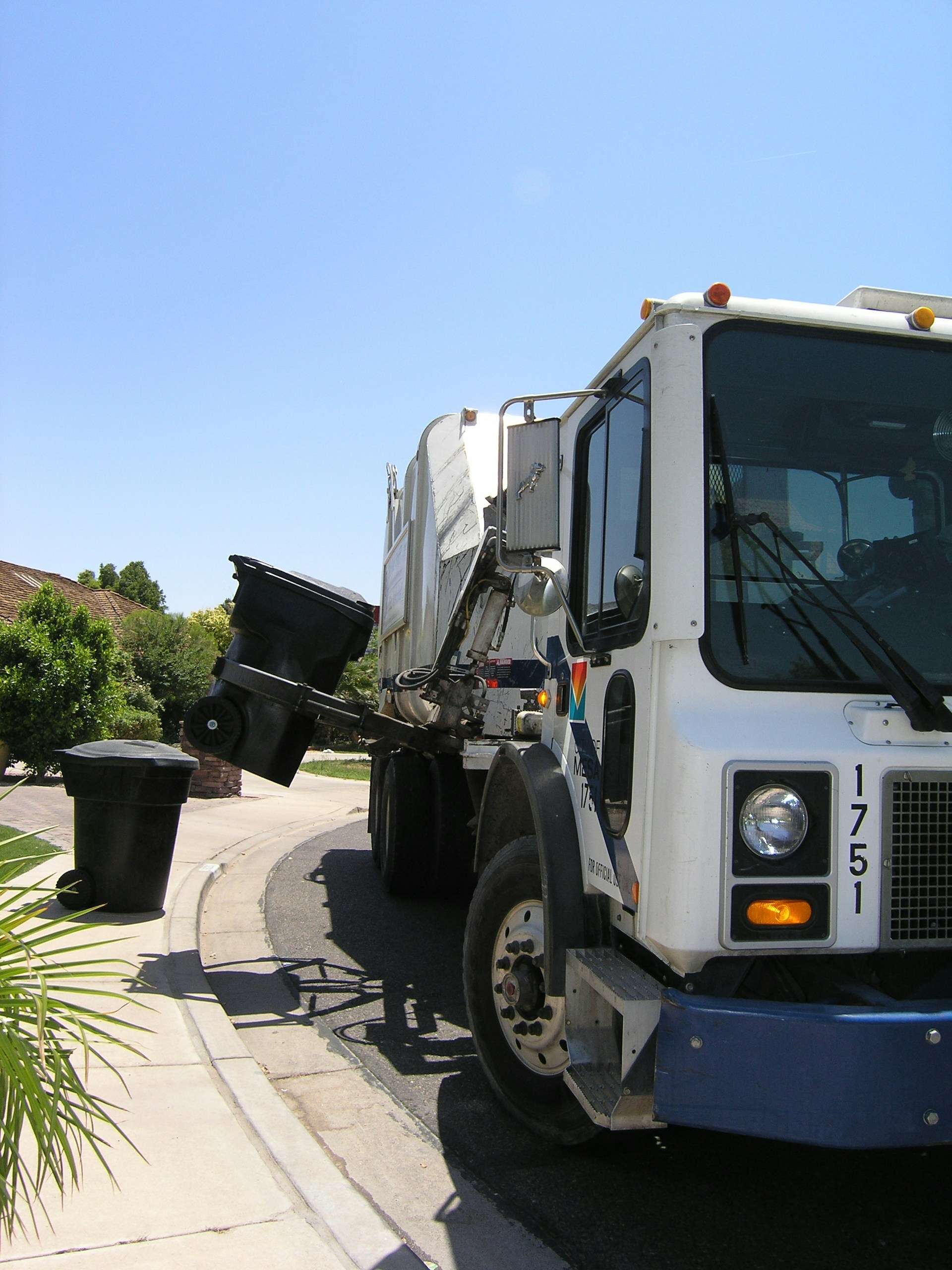Garbage truck picking up a trash bin on a residential street