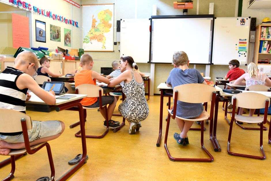 A young student working on a tablet at a classroom desk