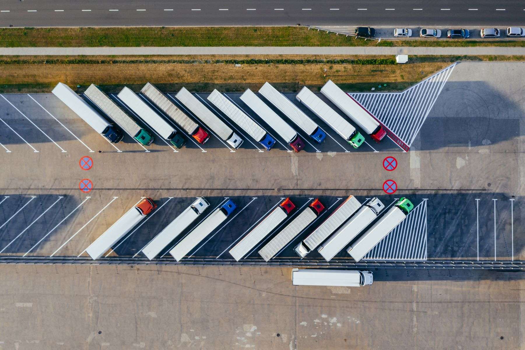 Aerial view of semi-trucks with trailers parked in rows at a commercial trucking yard
