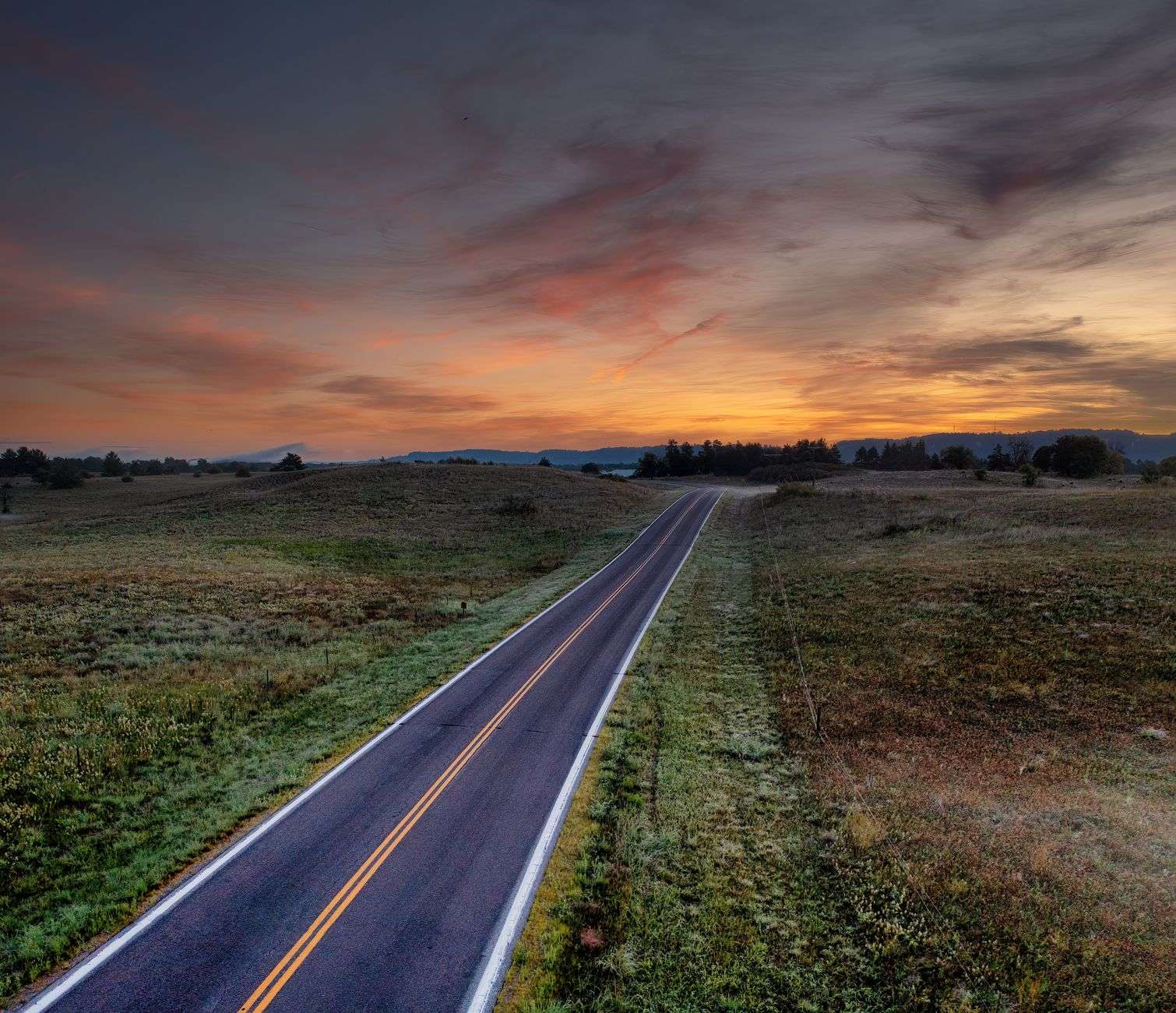 An open highway stretching through rural countryside in fading evening light