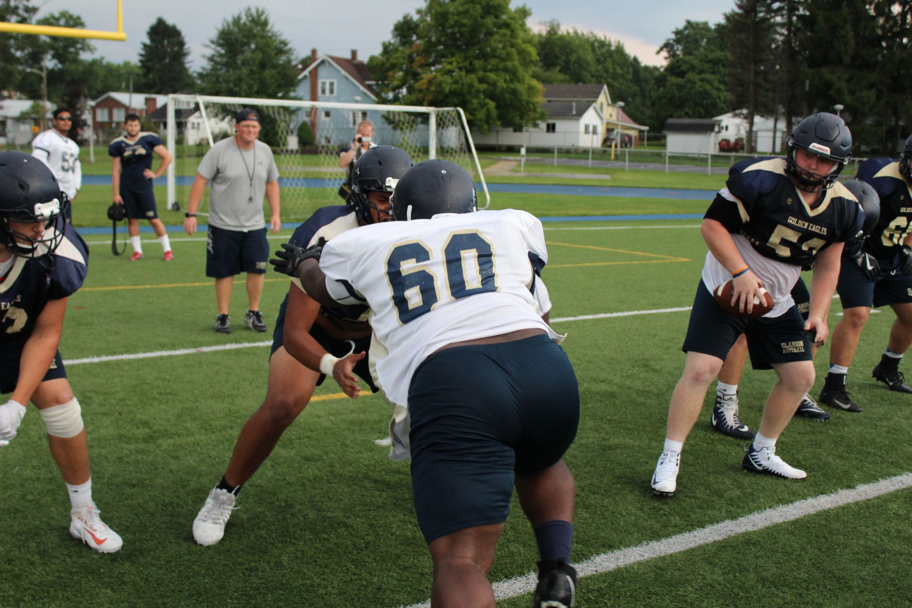 Football players driving a blocking sled during practice on a grass field