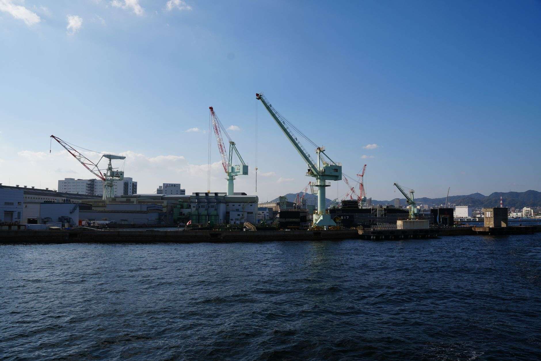Industrial shipyard cranes along a waterfront, illustrating a shipbuilding facility subject to an acquisition bid