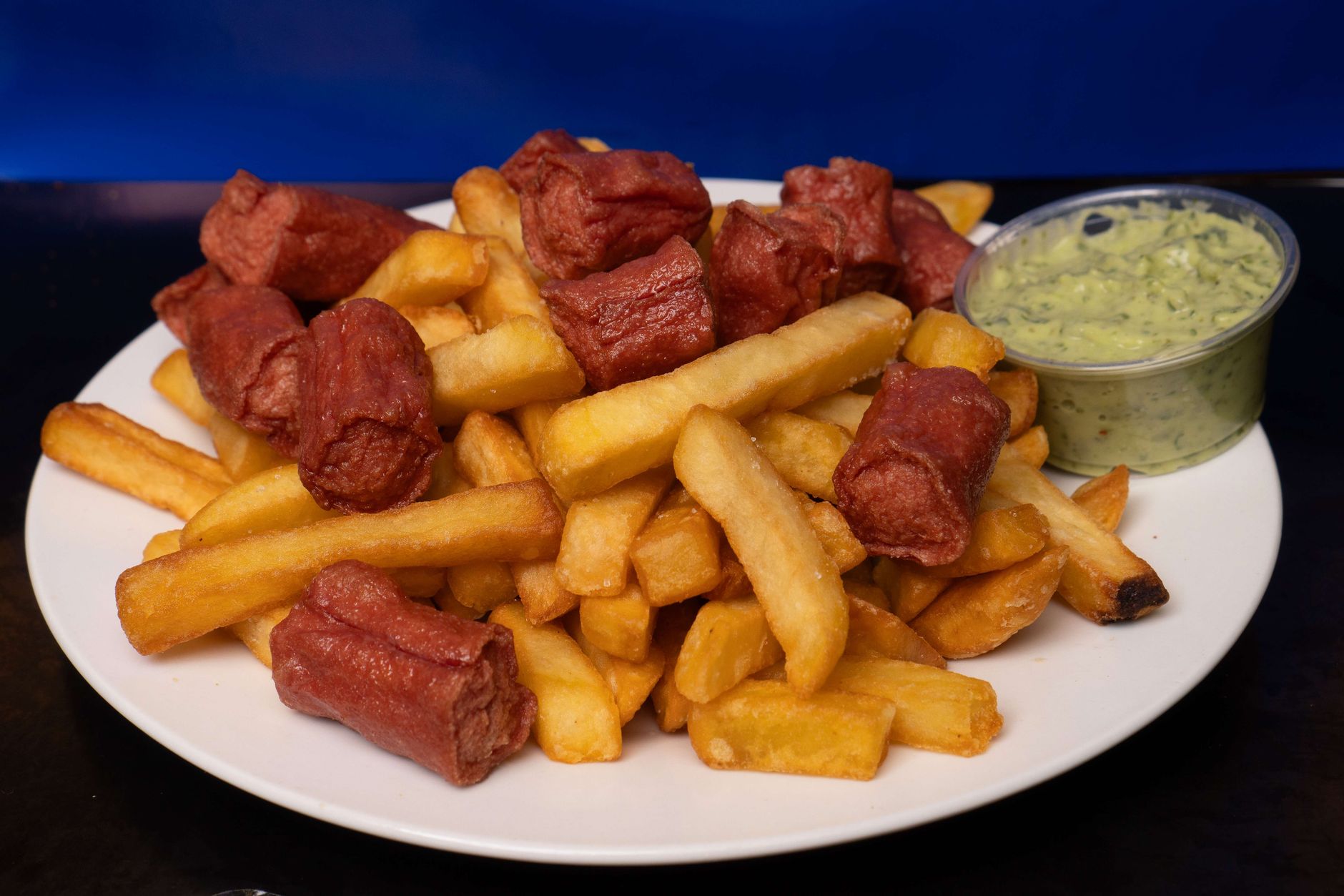 A loaded hot dog served with fries on a restaurant table