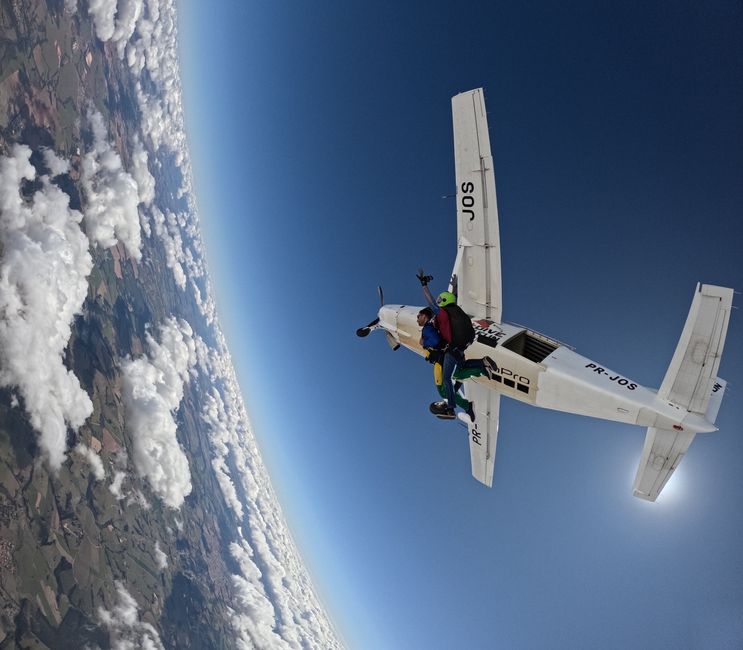 Tandem skydivers descending through the sky under an open parachute