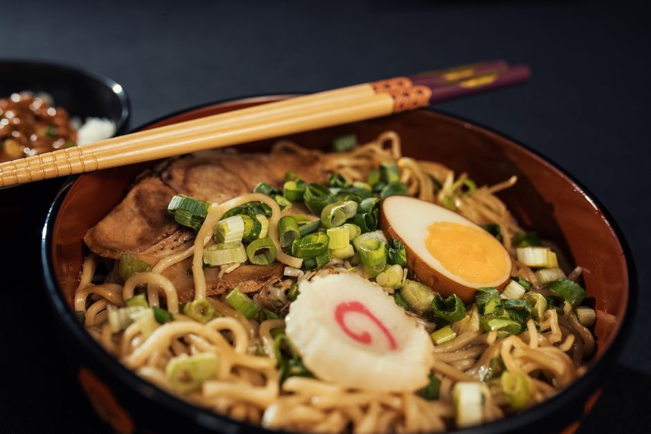 A steaming bowl of ramen noodles served with broth and toppings