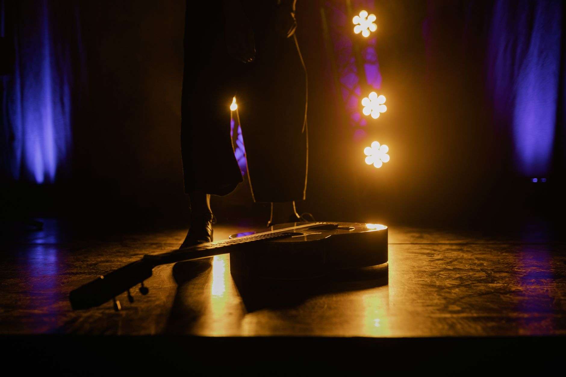 Acoustic guitar on a dimly lit stage under a single spotlight