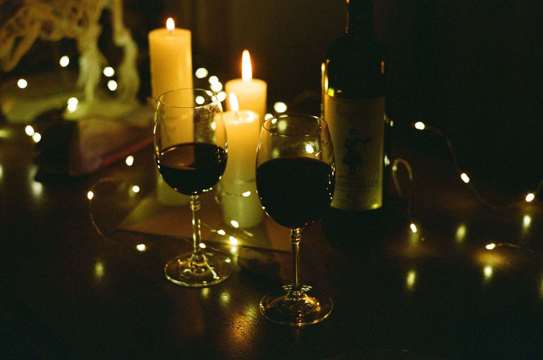 Glasses of red and white wine on a set dinner table with candles