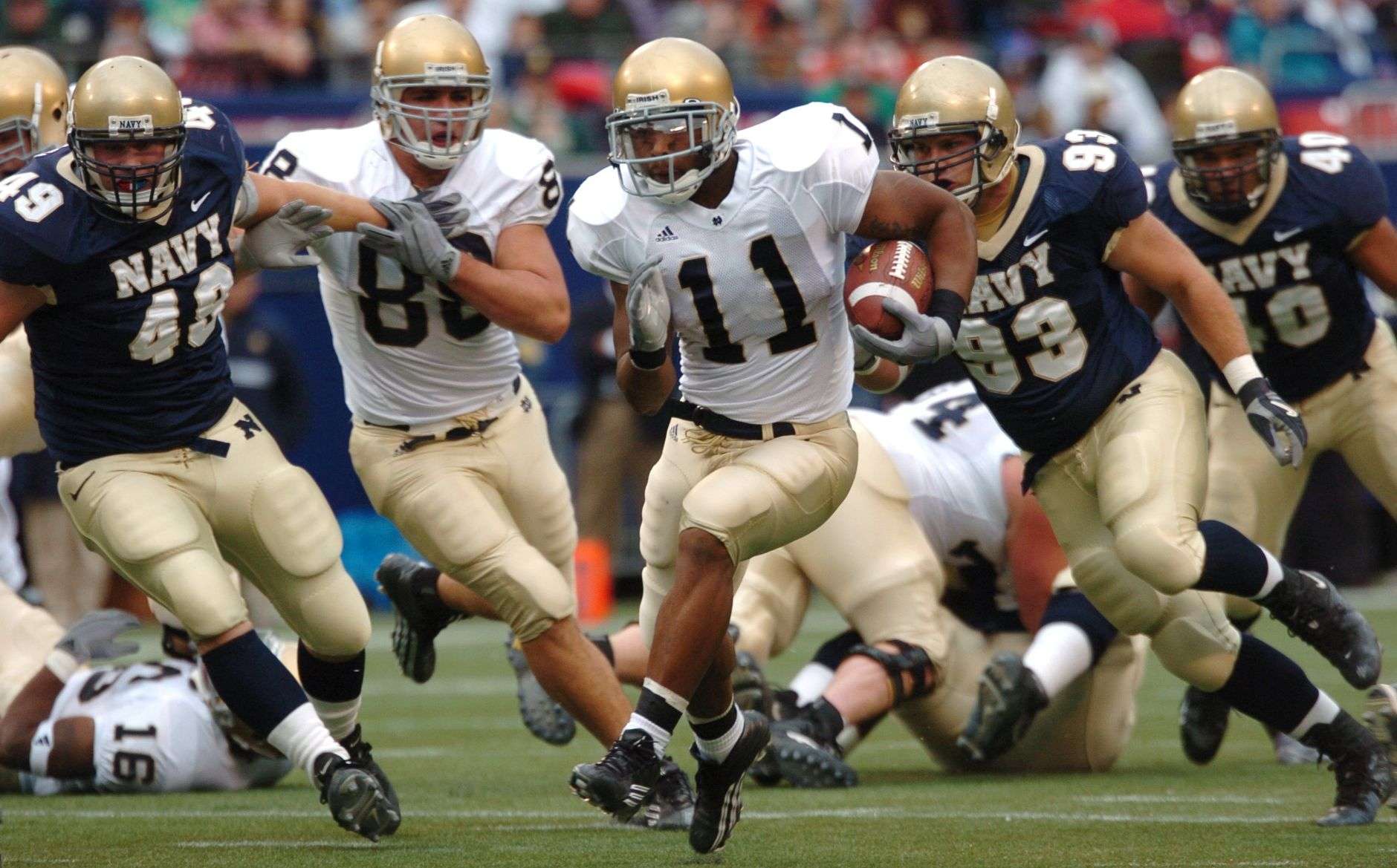 A running back carries the football upfield during a college football game