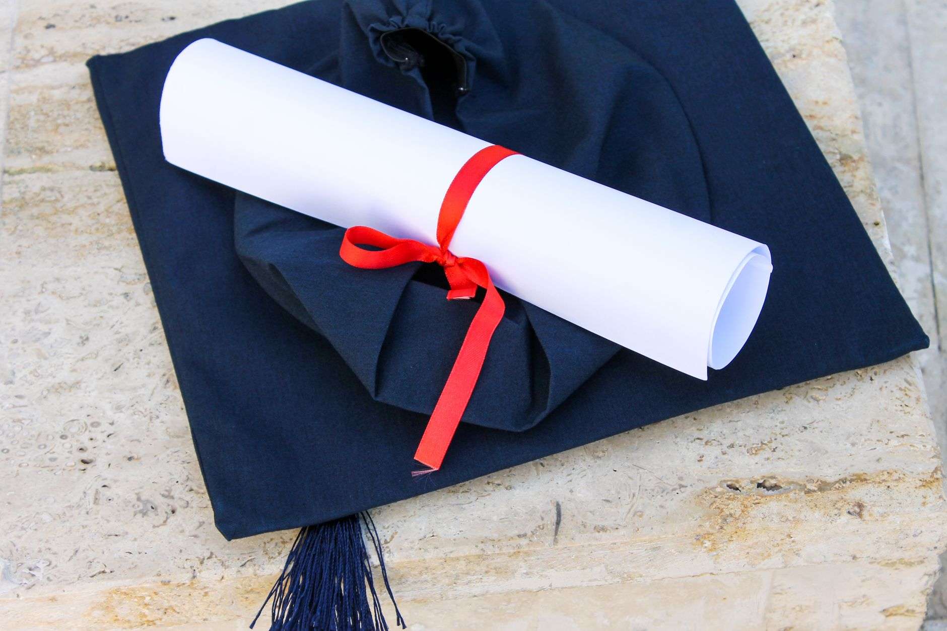 A graduation cap resting beside a rolled diploma