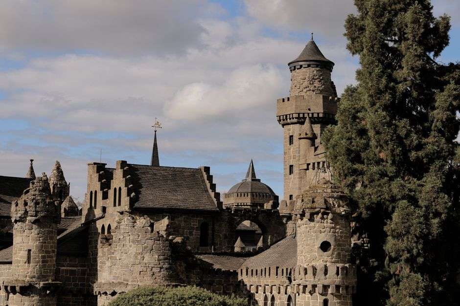 A fairytale-style stone castle cottage with towers surrounded by trees