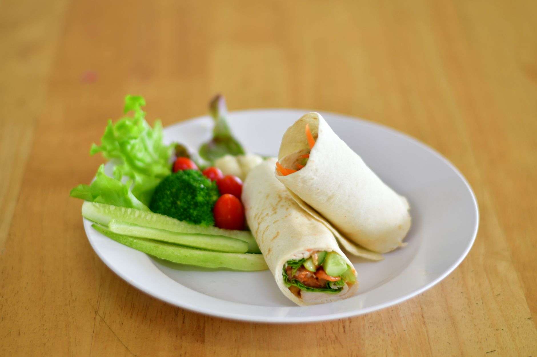 A fresh vegetable wrap and side salad on a cafe table