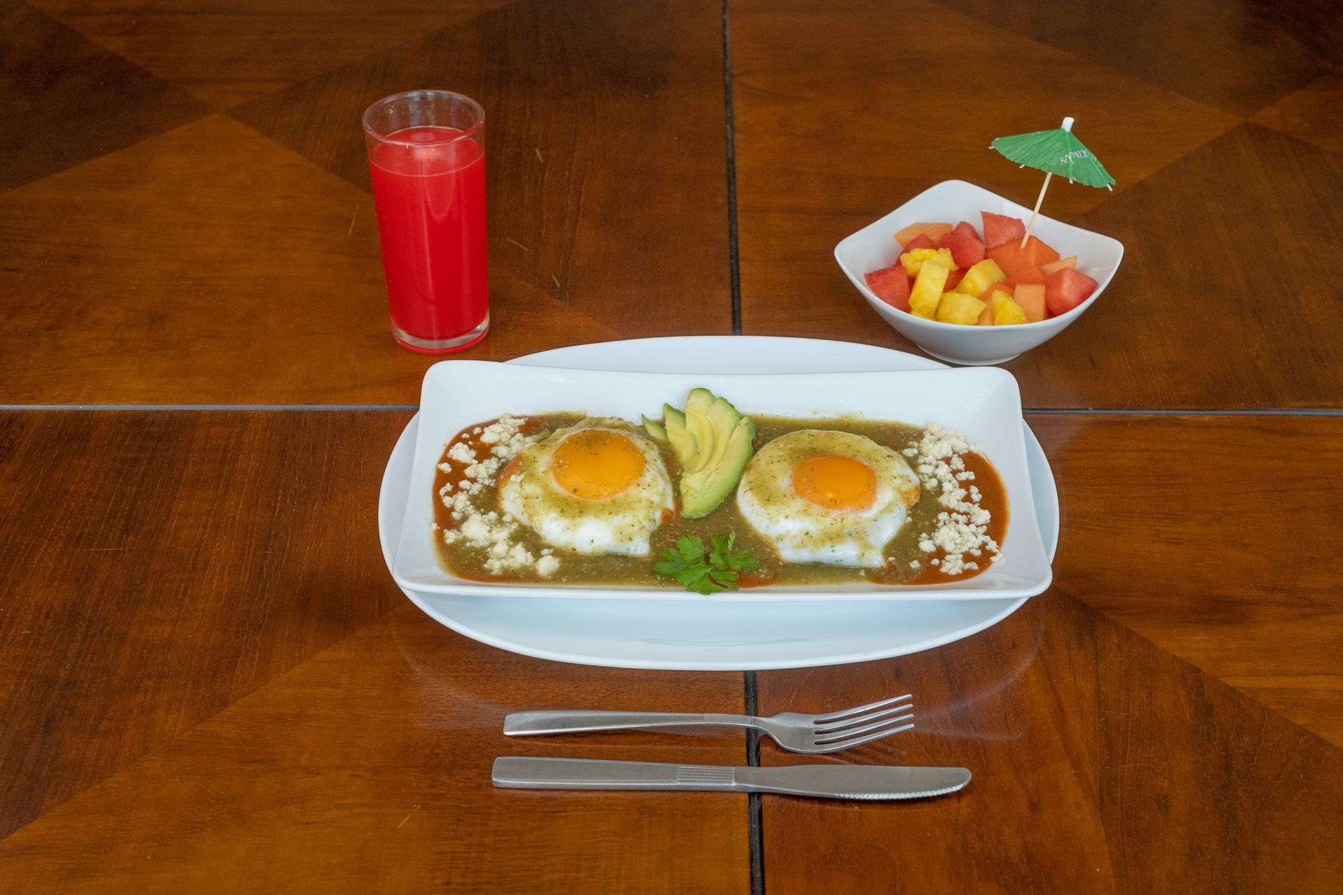 A plate of huevos rancheros with eggs, beans and avocado