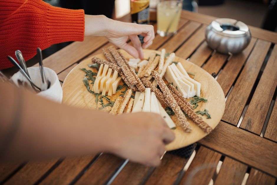 Golden crispy cheese straws arranged on a white serving plate