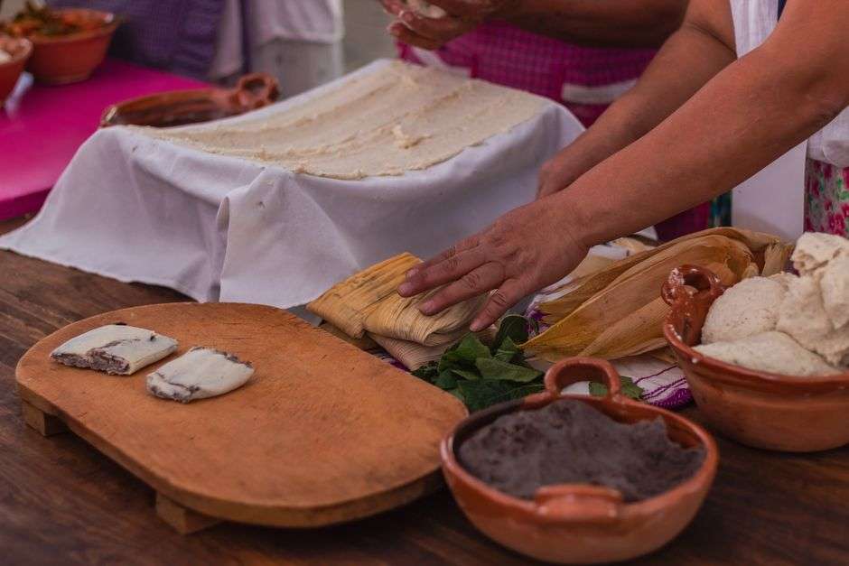Hand-rolled tamales wrapped in corn husks on a rustic table