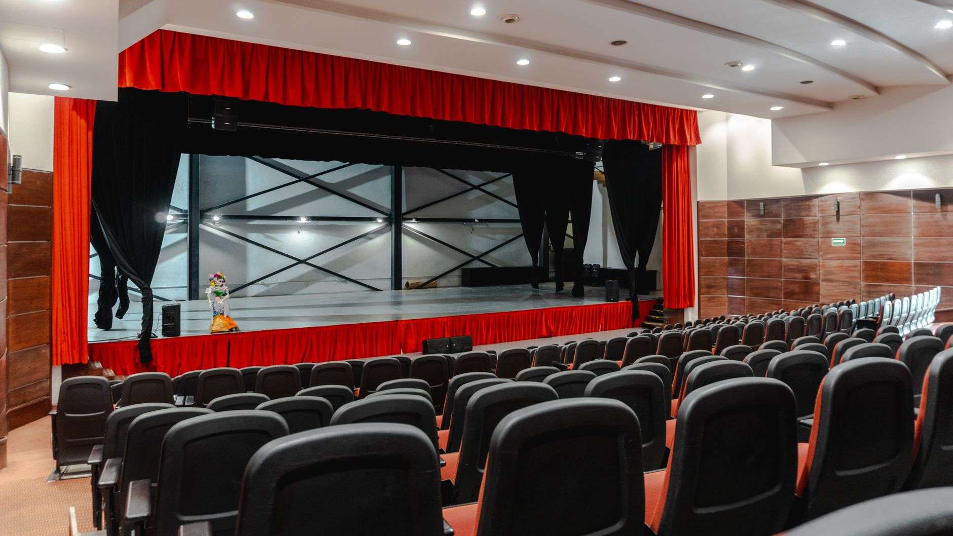An empty theater stage with curtains and rows of seats