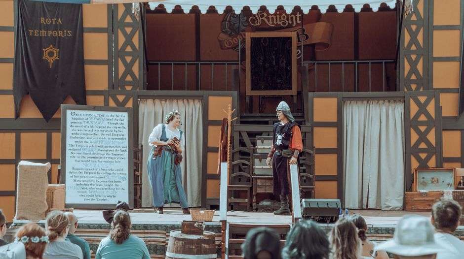 Performers on an outdoor theater stage at dusk