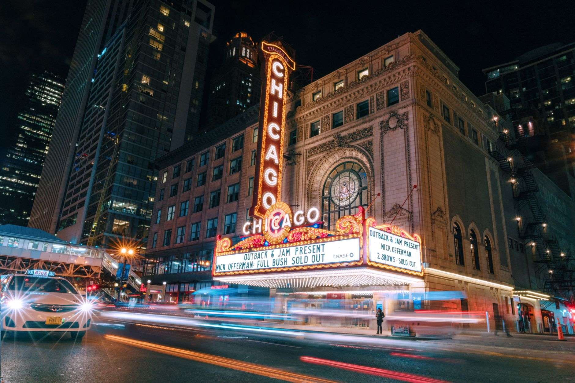 Brightly lit marquee of a historic downtown theater at night