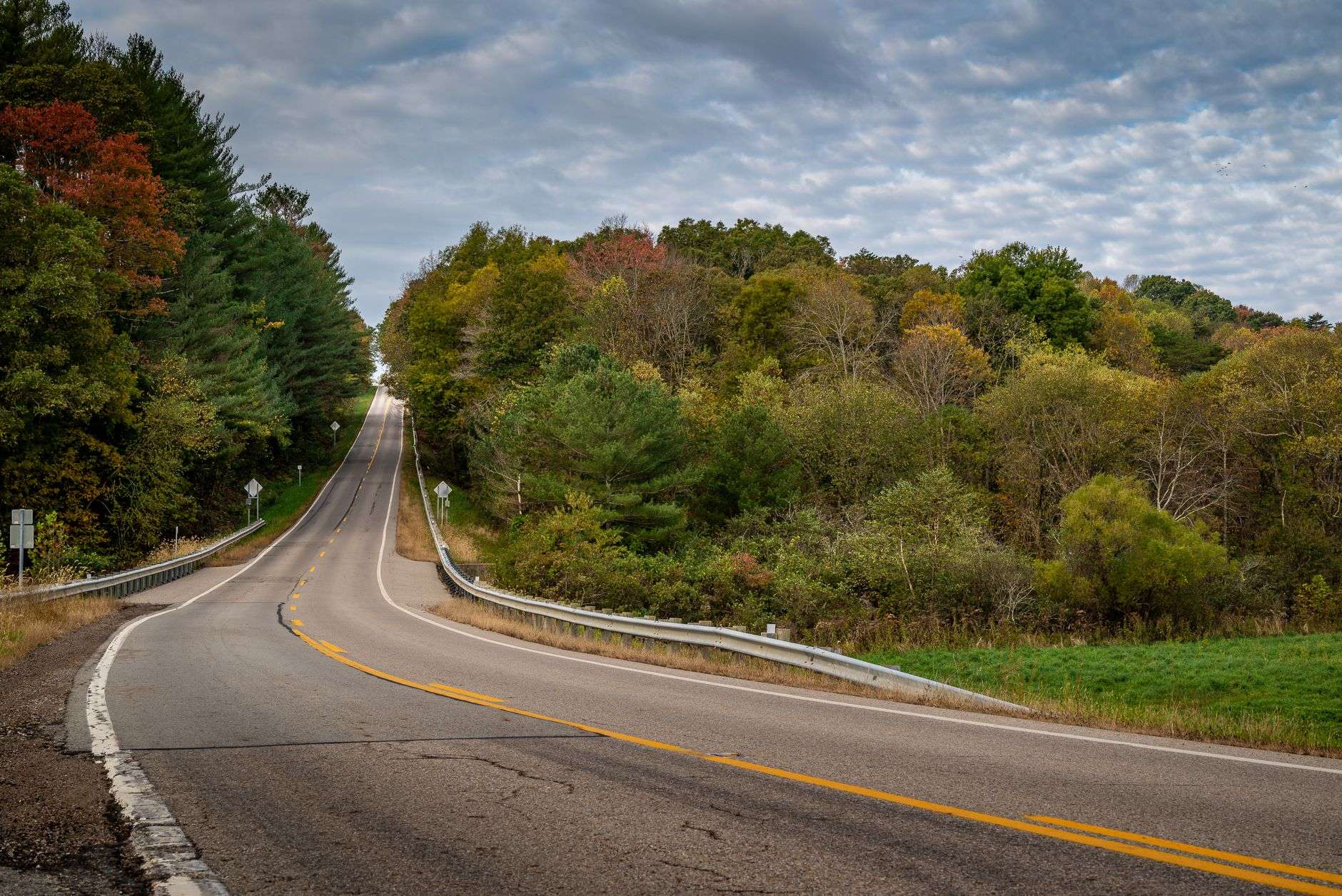An empty two-lane rural highway stretching toward the horizon in early morning light