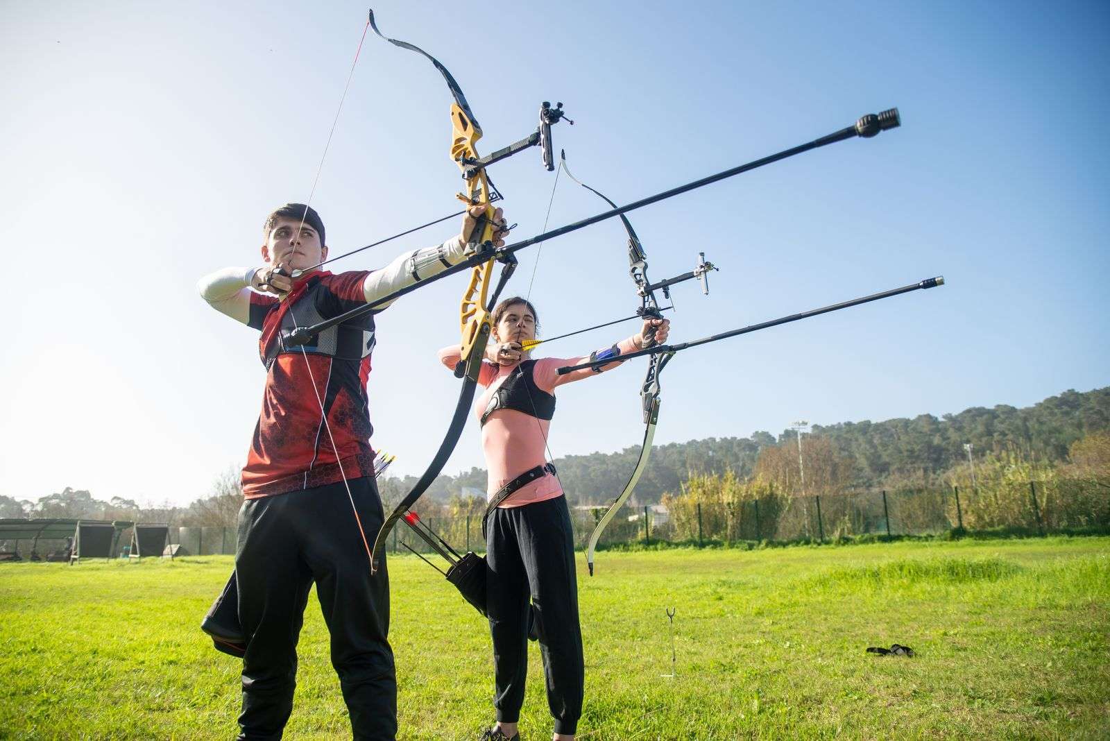 Archer drawing a bow and aiming outdoors