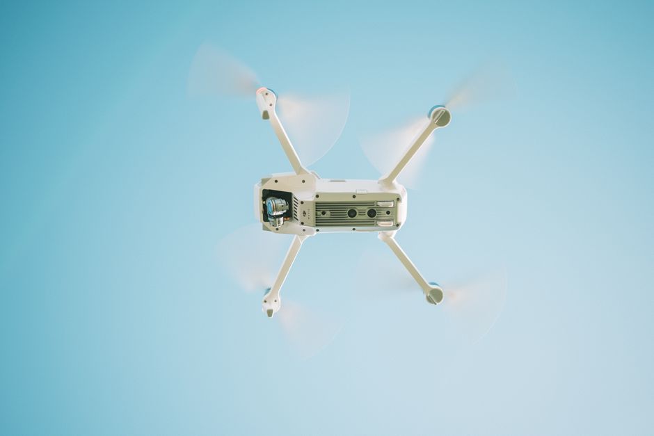 A quadcopter drone hovers against a clear sky during a research demonstration