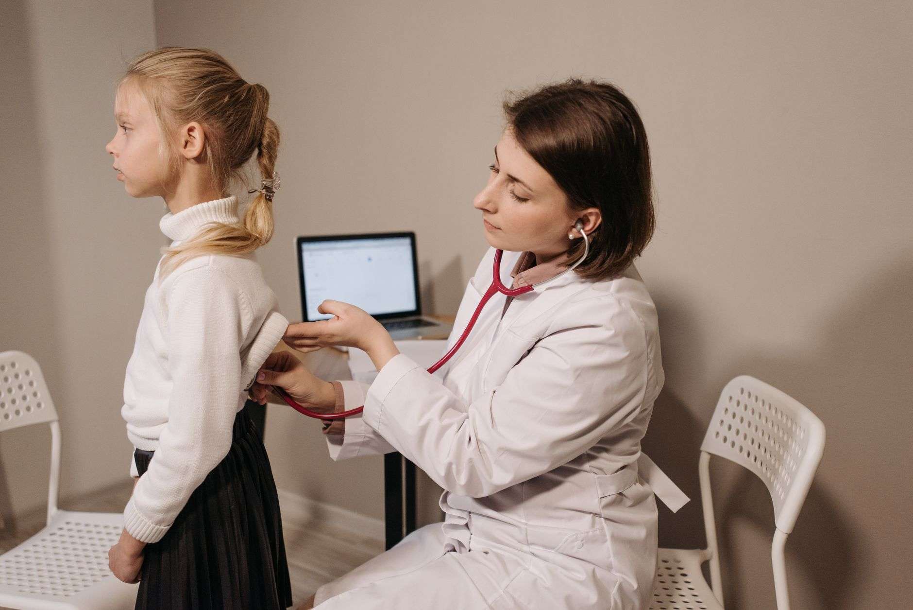 A pediatrician using a stethoscope during a child's checkup