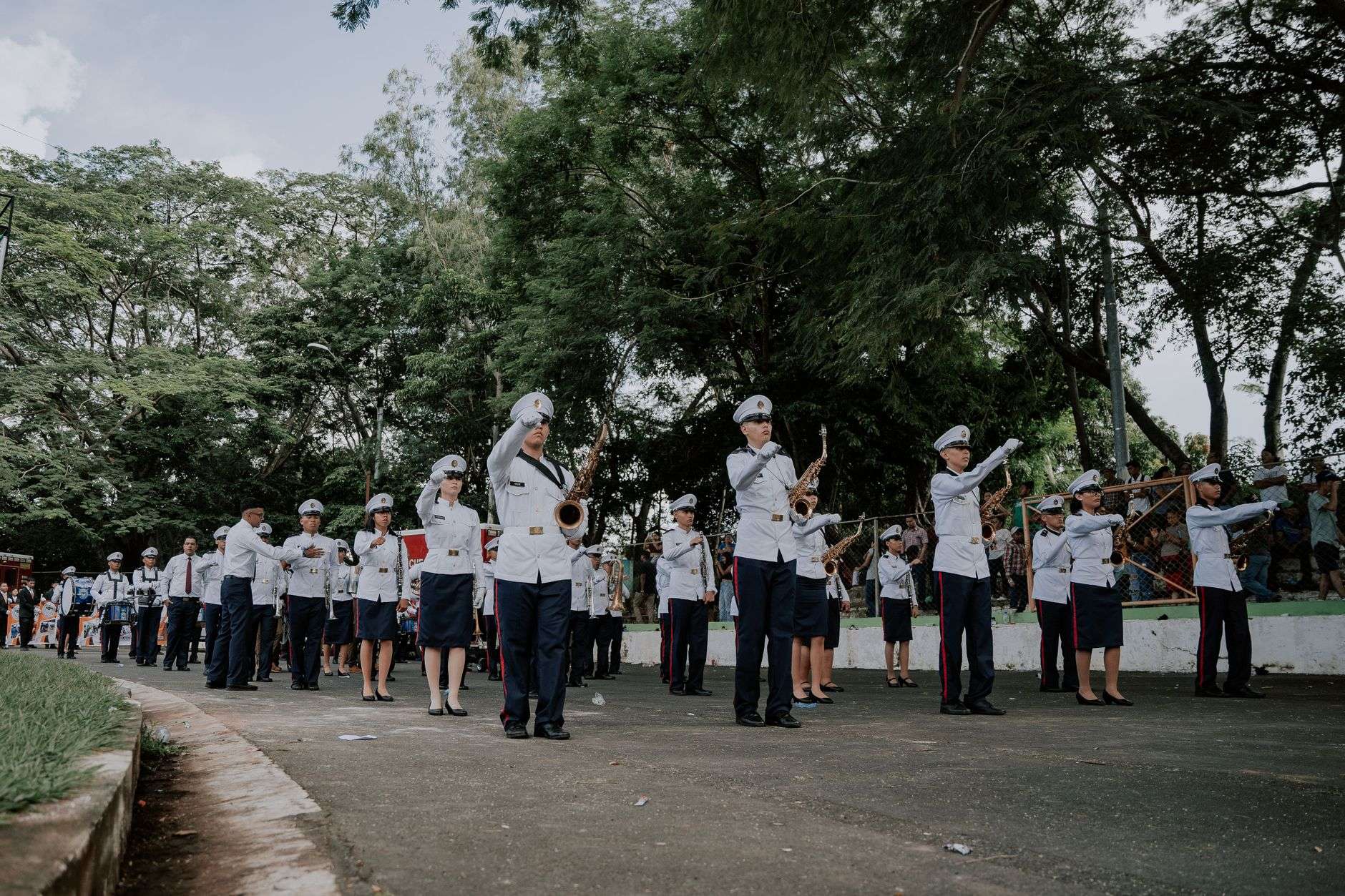 Members of a high school marching band performing in uniform with brass instruments