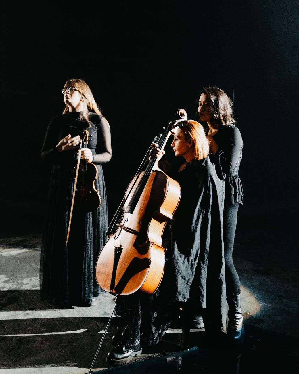 Musicians play violin and cello together on a dimly lit stage