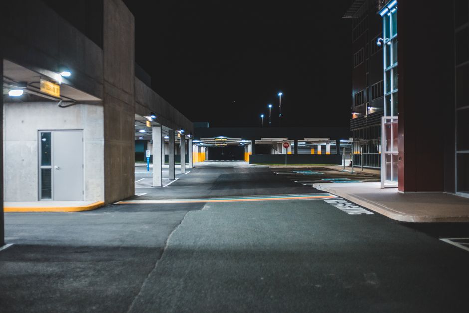 An apartment complex parking lot at night, with building lights in the background
