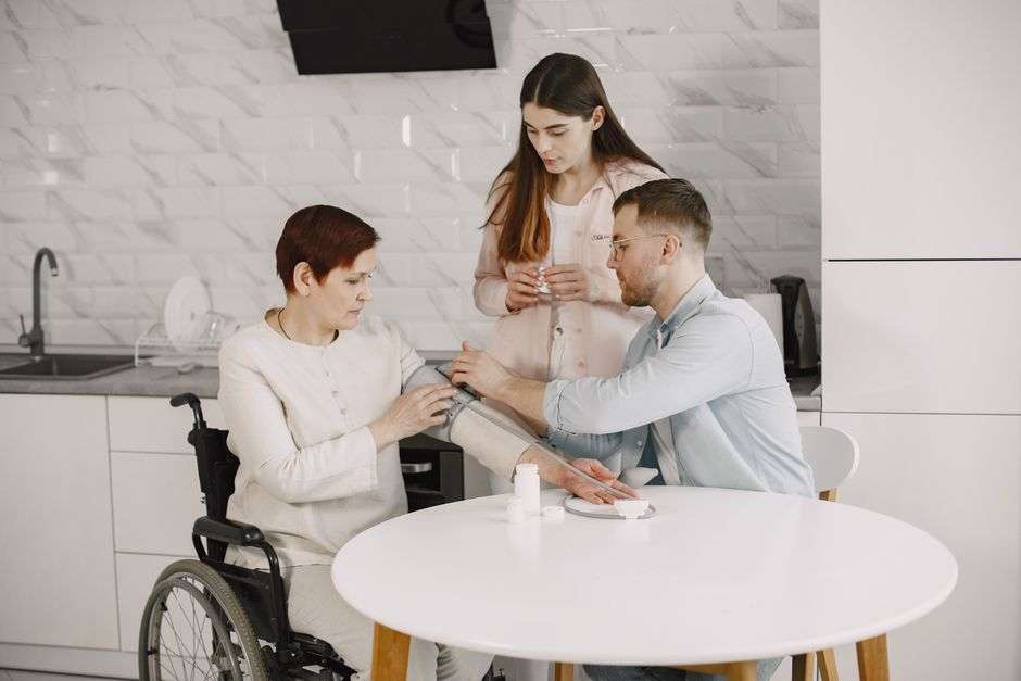 A young child in a wheelchair receives care at home from a family caregiver