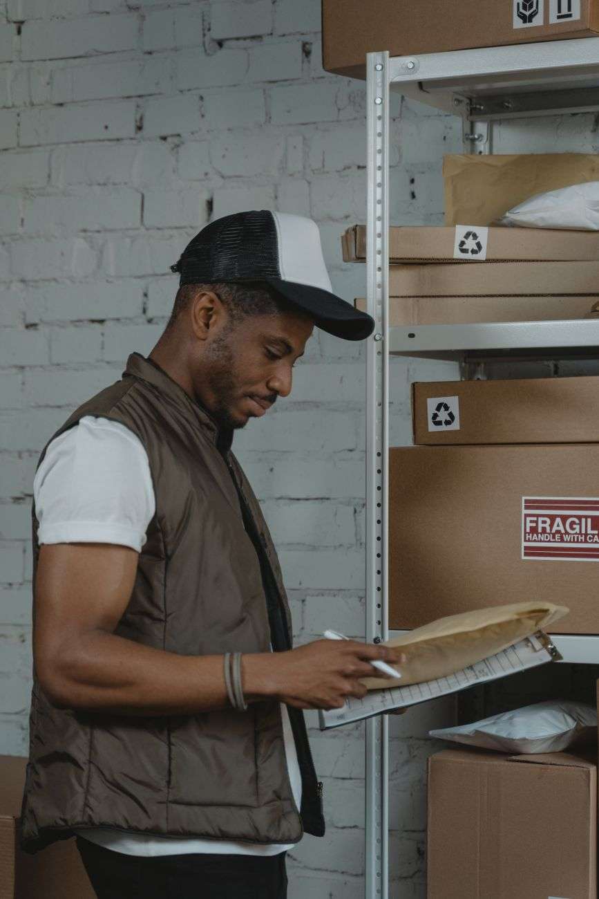 Warehouse employee checking packages and envelopes on a storage shelf