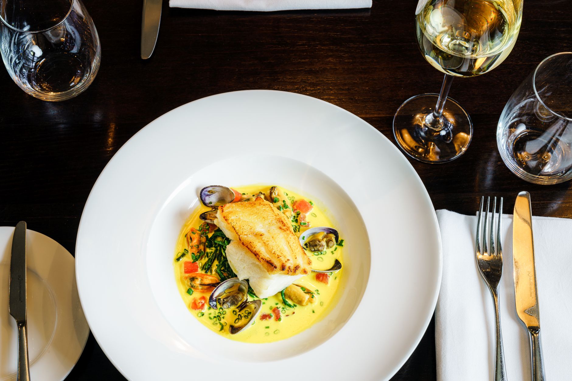 Plated seafood entree with a glass of red wine on a restaurant table