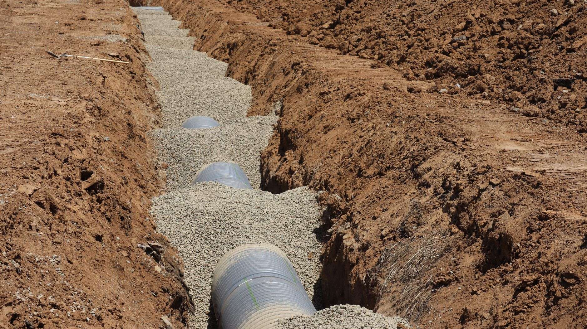 Large corrugated pipes laid in a gravel-lined construction trench