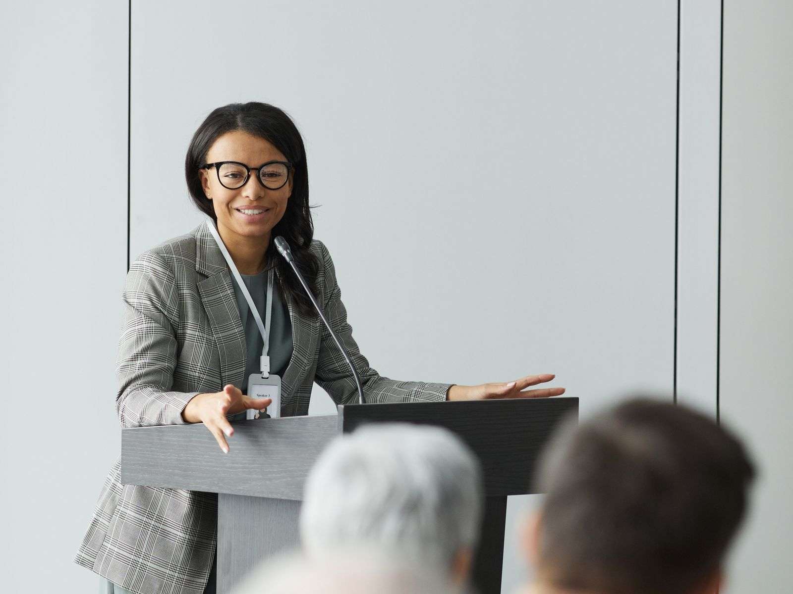 Woman speaking into a microphone at a podium in front of a seated audience