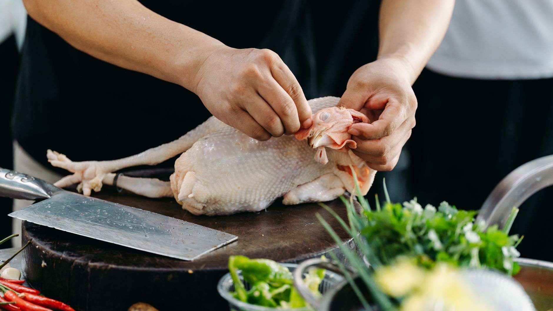 A group of friends chopping fresh vegetables and herbs together in a home kitchen