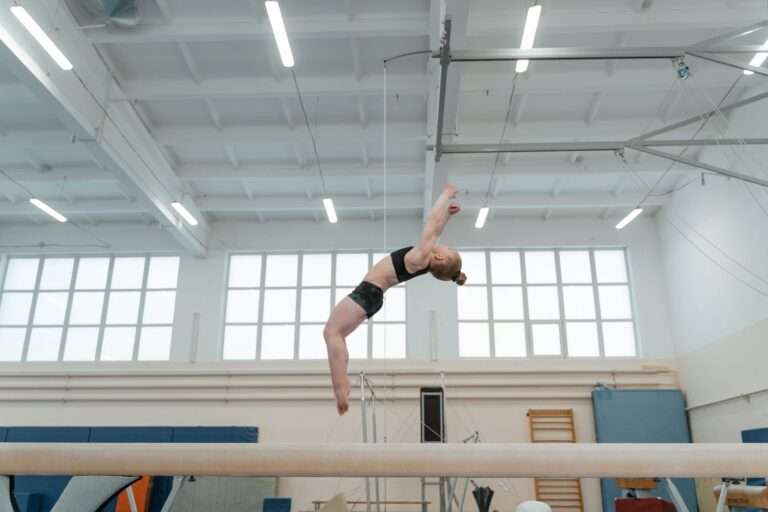 A young female gymnast performing an aerial skill in a training gym
