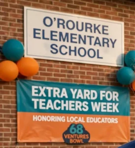 An elementary school sign on a brick wall above a banner reading Extra Yard for Teachers Week with balloons